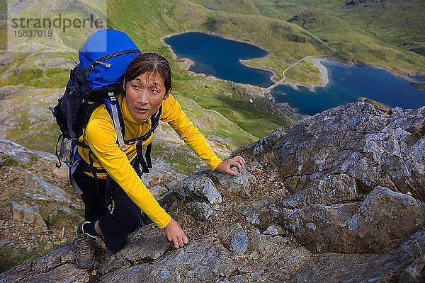 Frau klettert mit Rucksack auf den Snowdonia-Berg