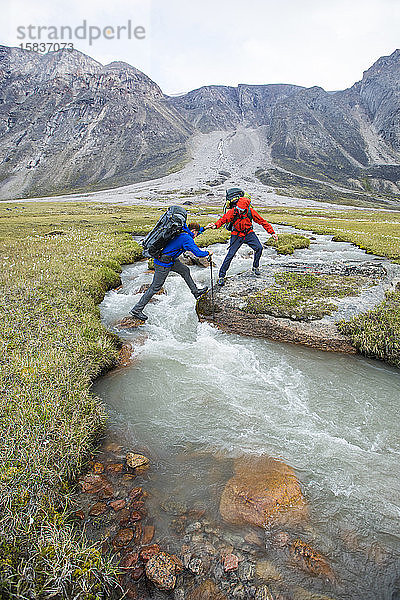 Rucksacktouristen helfen sich gegenseitig bei der Überquerung eines Flusses am Akshayak-Pass.