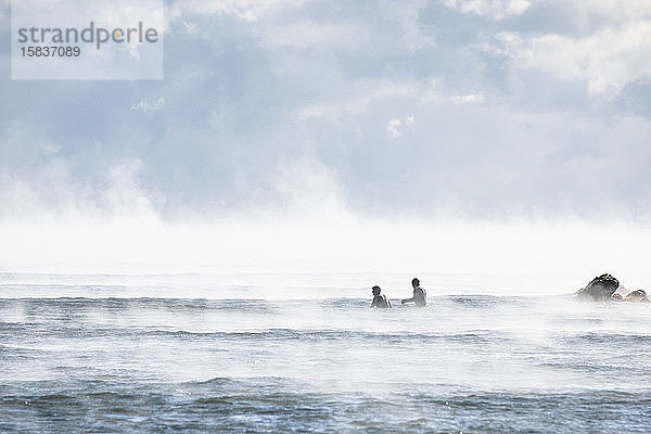 Männer surfen an einem arktisch kalten Winter-Surf-Tag mit Seerauch