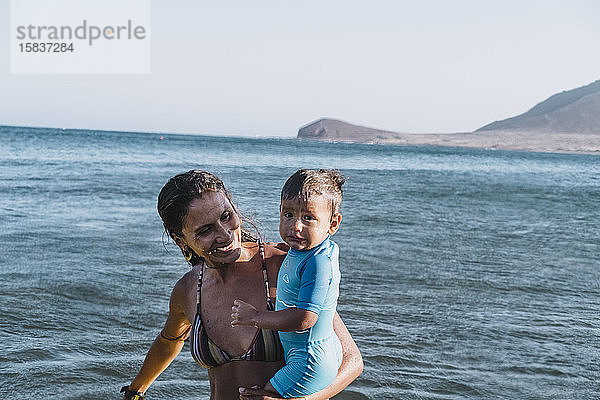 Eine Smiley-Mutter hält ihren Sohn am Strand