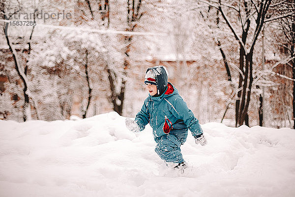 Junge läuft im Winter auf schneebedecktem Feld im Park