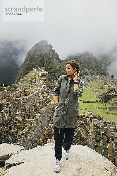 Eine junge Frau steht in der Nähe der Ruinen von Machu Picchu  Peru