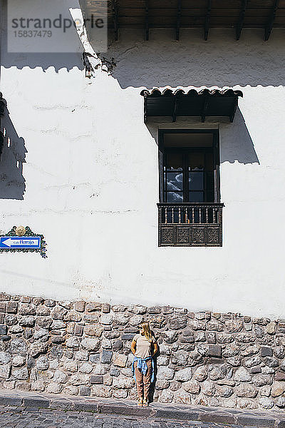 Eine junge Frau steht an einer weißen Wand in Cusco  Peru