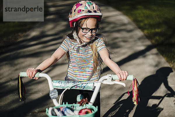 Kleines Mädchen fährt Fahrrad und trägt dabei Helm und Brille