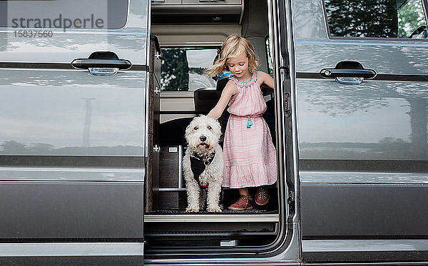 Porträt eines jungen Mädchens  das mit seinem Hund in einem Wohnmobil zeltet