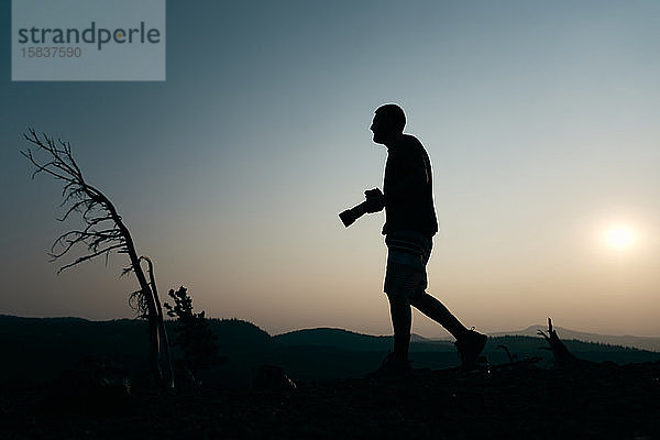 Silhouette eines Mannes mit Kamera bei Sonnenuntergang