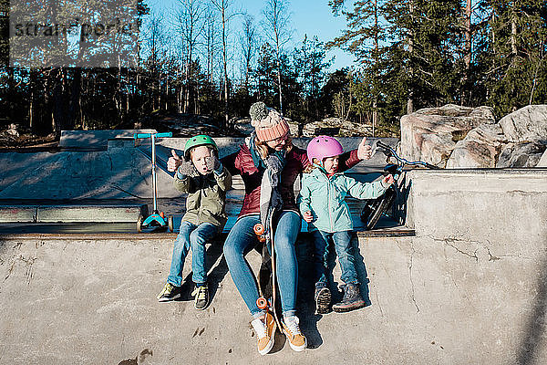Mama spielt mit ihren Kindern in einem Skatepark und hat Spaß