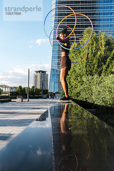 Junge Frau führt Hula-Hoop-Tanz mit vier Ringen in der Innenstadt auf