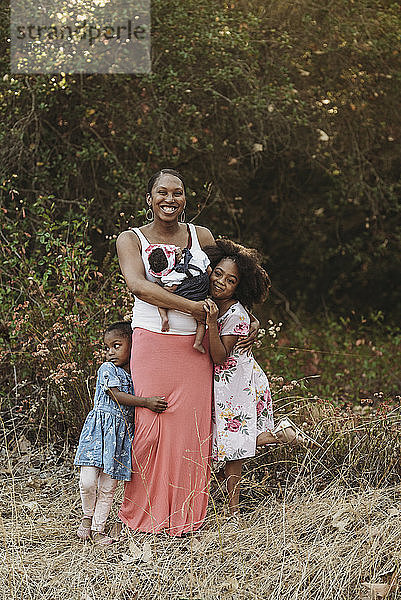 Porträt einer jungen Mutter und dreier Mädchen im Feld stehend