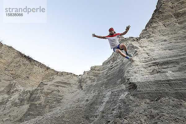 Ein Mann rennt auf einer sehr steilen Wand an einem alten Bergbauabfall aus Sand hinunter