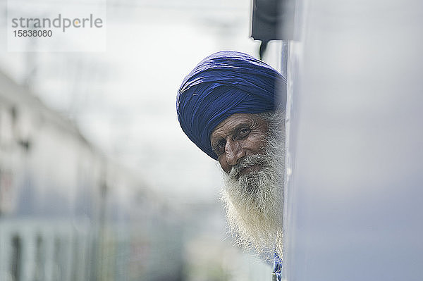 Alter Sikh-Mann schaut aus einem Fenster des Zuges
