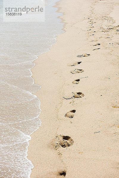 Fussspuren im Sand entlang eines einsamen Strandes