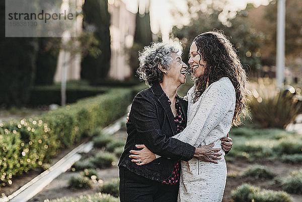 Aktive ältere Großmutter und erwachsene Tochter umarmen sich draußen