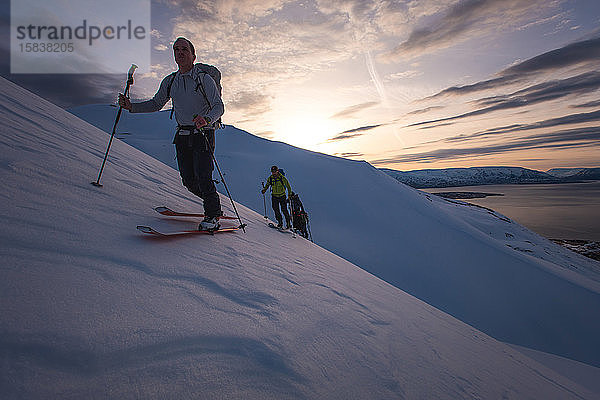 Personengruppe beim Skilanglauf bei Sonnenaufgang in Island