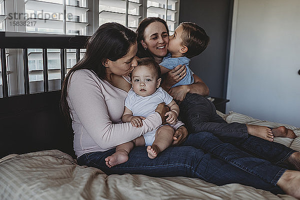 Glückliche nicht-traditionelle Familie mit zwei Müttern und Kindern  die zu Hause kuscheln