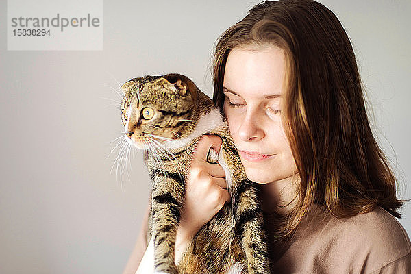 Junge Frau hält schöne Katze auf weißem Hintergrund