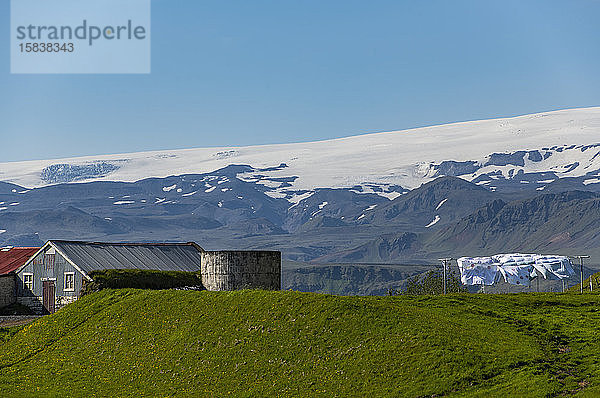 Bauernhaus an der Südküste in Island mit Gletscher im Hintergrund