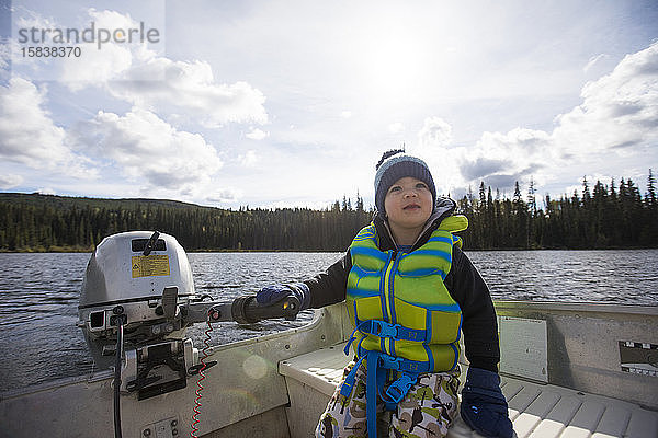 Kleinkind Junge fährt Motorboot auf dem See.
