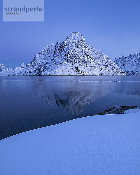 Der Berg Olstind erhebt sich über der Winterlandschaft des Reinefjord  Reine  Lofoten  Norwegen