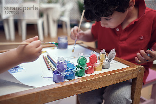 Kinder  die in einem Innenhof spielen und mit Wasserfarben malen