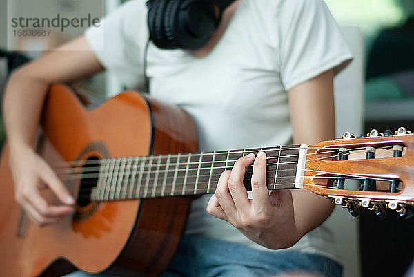 Frauenhände beim Spielen der akustischen Gitarre  Nahaufnahme