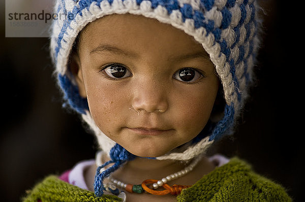 Süßes kleines Kind mit Wollmütze und traditionellem Gewand