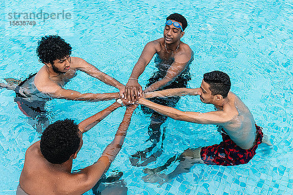 Gruppe junger Leute  die ihre Hände in einem Kreis in einem Becken sammeln
