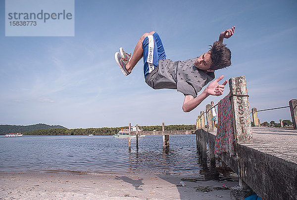 Parkour-Sportler springt vom Pier des Strandes