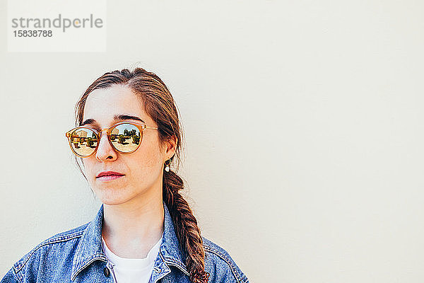 Nahaufnahme einer attraktiven jungen Frau mit Sonnenbrille auf pastellfarbenem Hintergrund