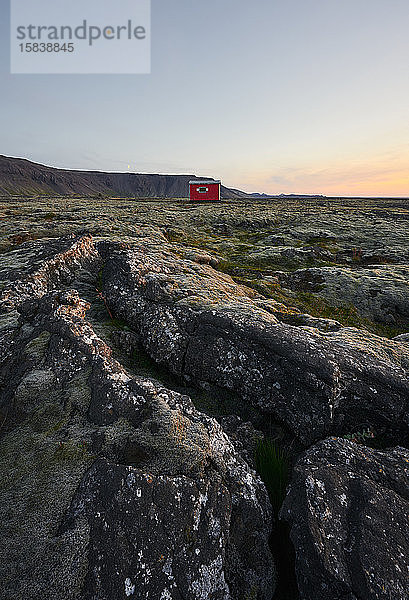 Malerische Landschaft einer Hütte auf vulkanischem Terrain bei Sonnenuntergang