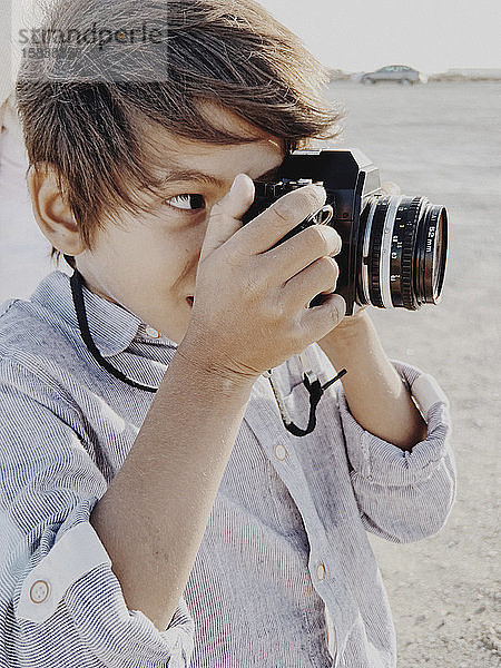 Nahaufnahme des Porträts eines Kindes  das mit einer Oldtimer-Kamera fotografiert