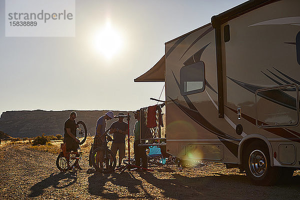 Eine Gruppe von Jungs  die am Heck eines Wohnmobils auf Mountainbikes arbeiten.