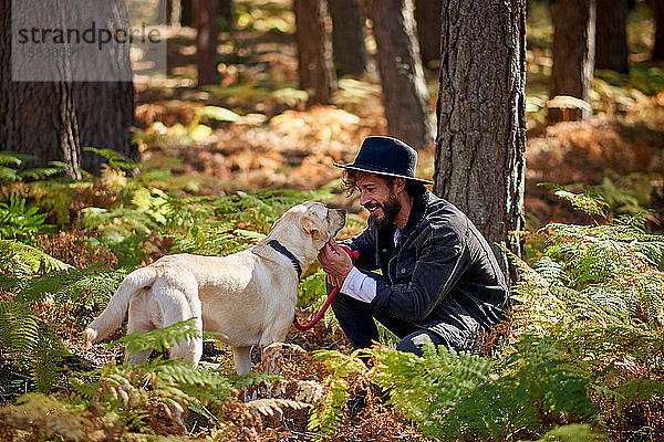 Porträt eines jungen tätowierten Mannes mit seinem Hund im Wald