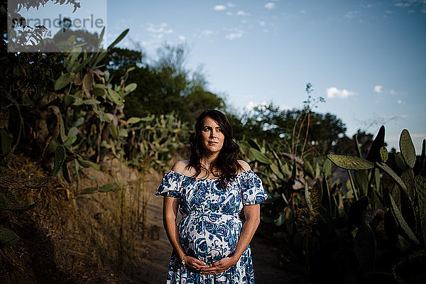 Schwangere Frau Mitte Dreissiger Jahre posiert im Kaktusgarten