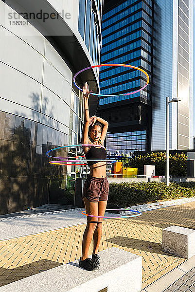 Junge Frau führt Hula-Hoop-Tanz mit vier Ringen im Stadtgebiet auf