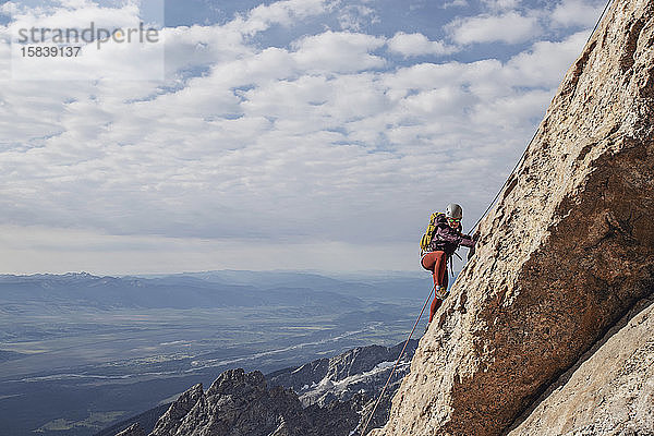 Geschnürte Bergsteigerin besteigt eine Klippe in den Tetons  Wyoming