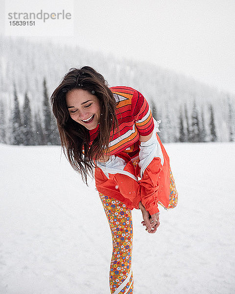Stilvolle junge Frau lacht im Schnee