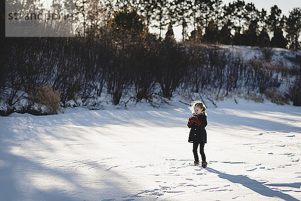 Kleines Mädchen spielt auf gefrorenem  schneebedecktem See