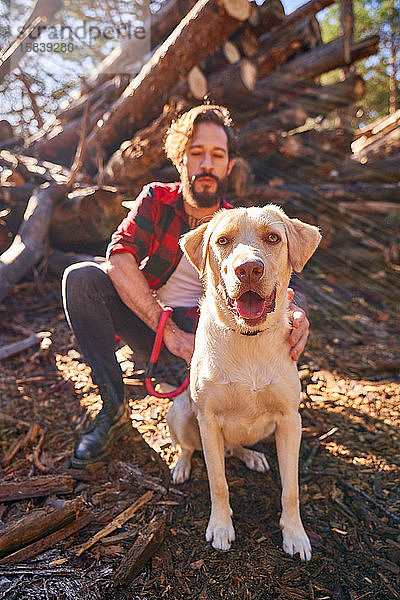 Porträt eines jungen tätowierten Mannes mit seinem Hund im Wald