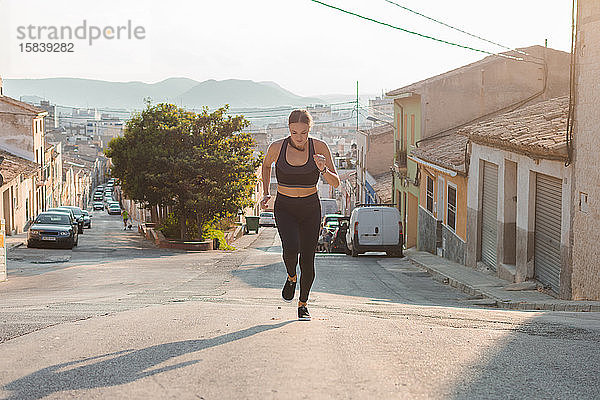 Junge Frau läuft in einer Straße einer Stadt. Weibliche Athletin  Sportkonzept