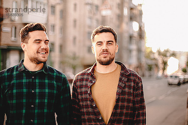 Porträt der glücklichen Zwillingsbrüder  die im Sommer auf der Straße der Stadt stehen