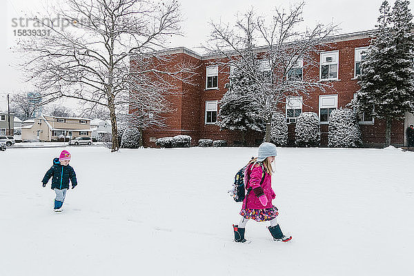 Zwei Kinder gehen im Schnee zur Schule.