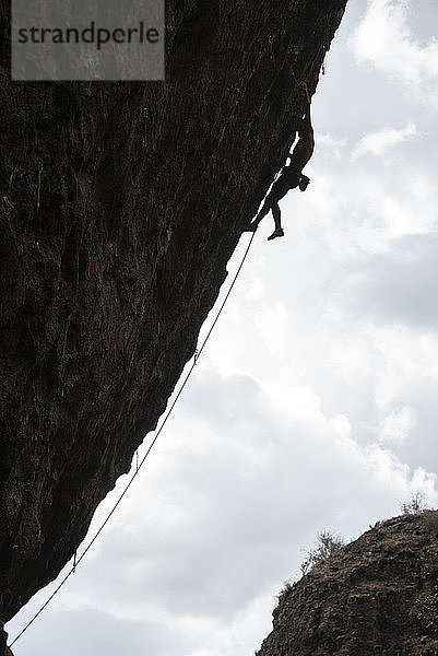 Silhouette eines Mannes beim Klettern an einer überhängenden Wand in Jilotepec