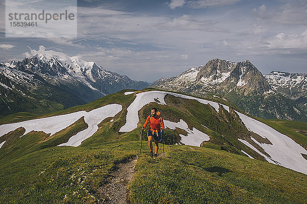 Junge Männer wandern in den französischen Alpen mit dem Mont Blanc als Kulisse.