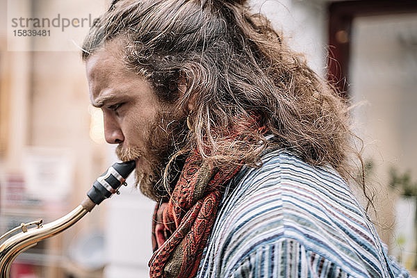 Saxophonist mit langen Haaren und Bart spielt auf der Straße