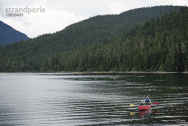 Mann und Kind paddeln ein Kanu auf einem Bergsee