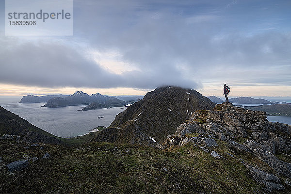 Wanderin überblickt Berglandschaft von Middagstind aus  FlakstadÃ¸y  Lofoten-Inseln  Norwegen