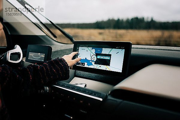 Jungen  die mit der Hand auf eine GPS-Satellitennavigationskarte in einem Elektroauto zeigen