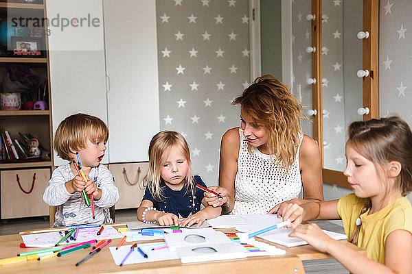 Mutter mit kleinen Kindern  die mit Filzstiften zeichnen