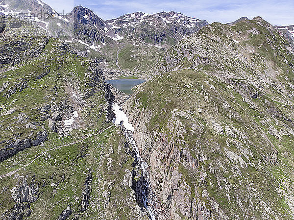 Luftaufnahme eines Alpensees und eines schneebedeckten Wasserfalls